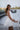Girl wearing Amara white one piece mini dress with bow back