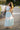 Girl wearing in a light green tow piece crop top and maxi sksirt with lace detailing standing on a path with blurred background