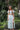 Woman in a light green dress standing in a garden