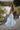 Girl wearing in a light green two piece crop top and maxi skirt with lace detailing standing on a path with blurred background and back shot facing towards camera